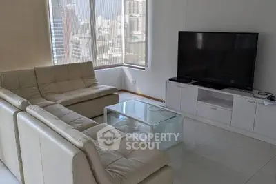 Modern living room with large TV and city view from corner windows.