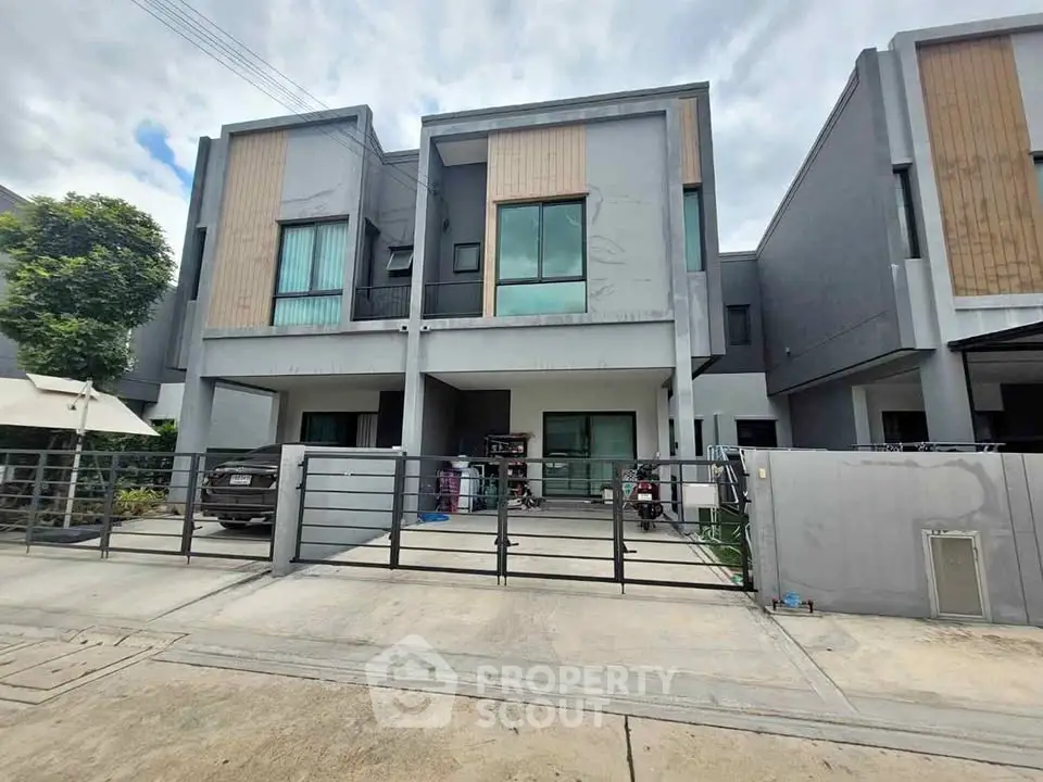 Modern two-story townhouse with sleek design and spacious driveway in a suburban neighborhood.