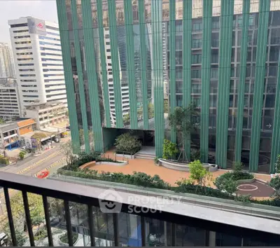 Stunning urban view from a high-rise balcony overlooking modern architecture and lush greenery.