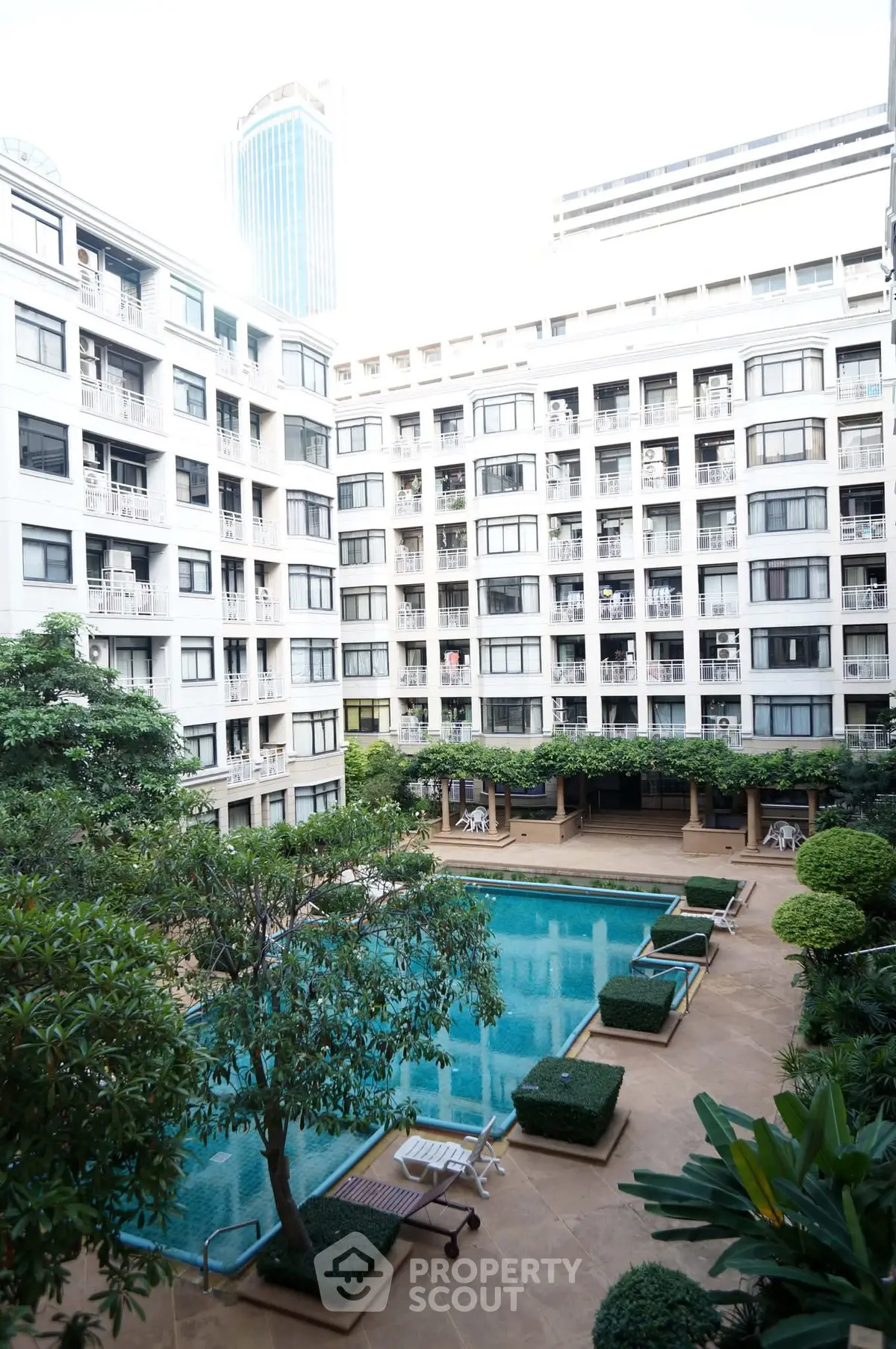Luxurious apartment complex with a stunning pool and lush greenery, perfect for urban living.
