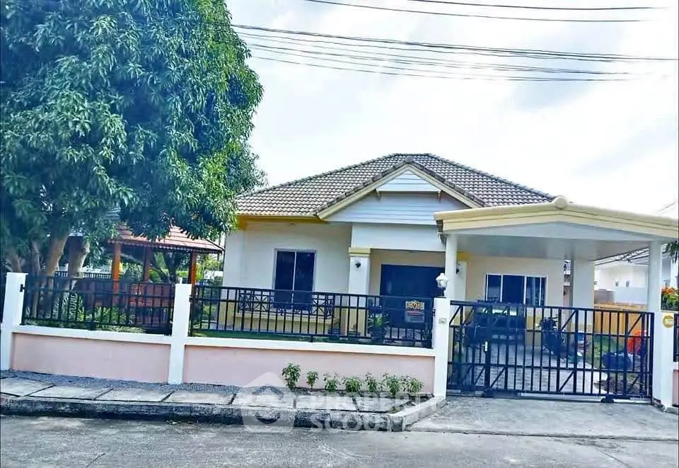 Charming single-story house with gated driveway and lush greenery in a serene neighborhood.