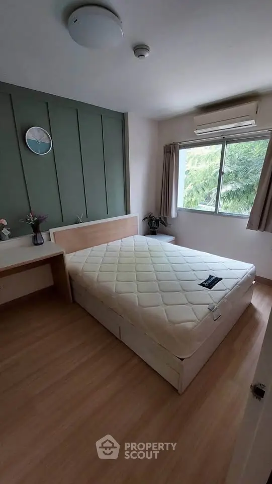 Cozy bedroom with natural light and minimalist decor, featuring a comfortable bed and wooden flooring.