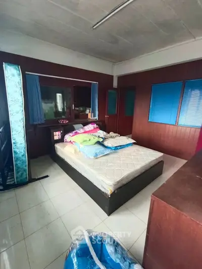 Spacious bedroom with large windows and ample natural light, featuring a comfortable bed and modern decor.