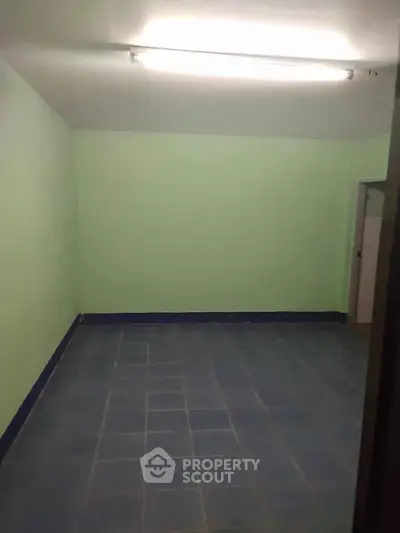 Spacious empty room with tiled floor and light green walls, ideal for customization.