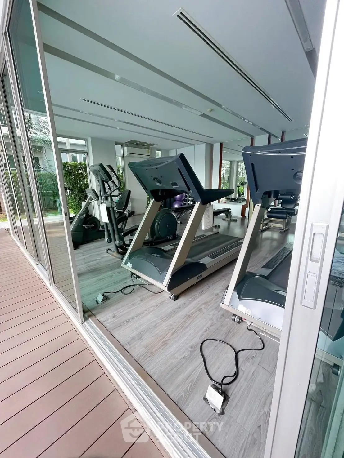 Modern gym with state-of-the-art equipment and large windows offering garden views.