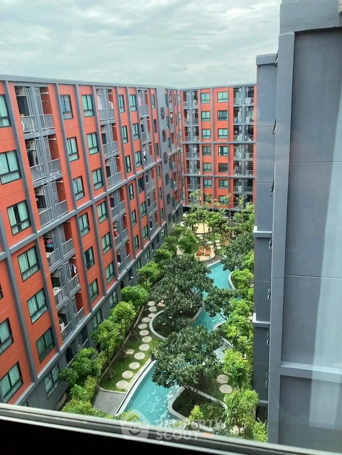 Modern apartment complex with lush garden and pool view from above.