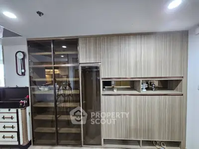 Modern kitchen with sleek cabinetry and glass display shelves in a contemporary apartment.
