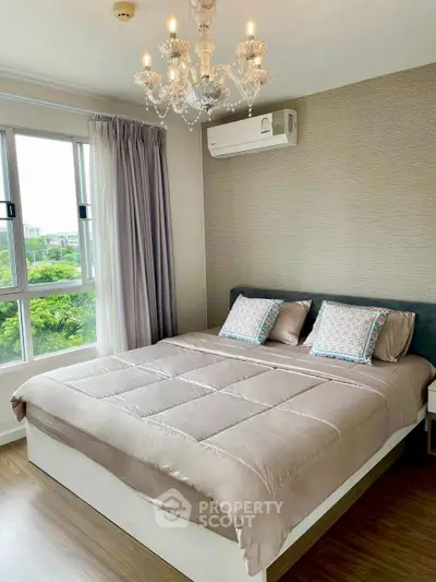 Elegant bedroom with chandelier and large window offering lush green views.