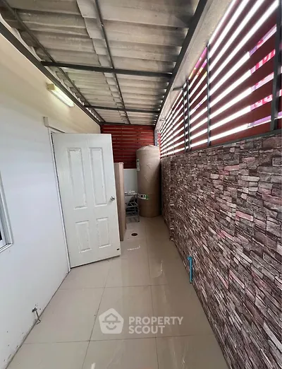 Covered outdoor area with tiled floor and stone accent wall, ideal for storage or utility use.