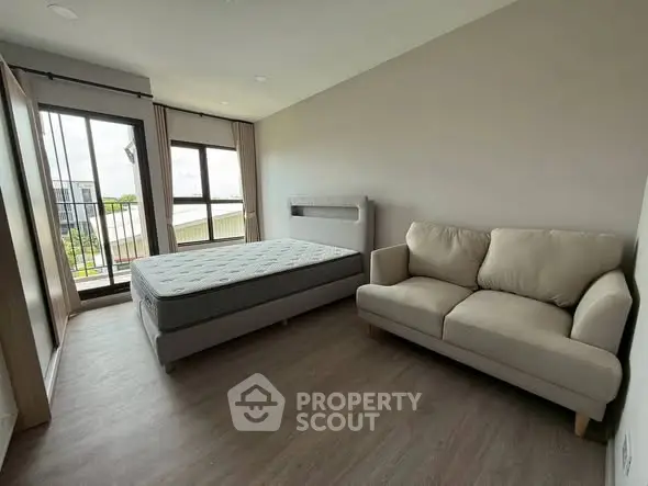 Spacious bedroom with balcony access and cozy sofa in modern apartment