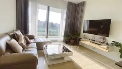 Modern living room with large windows and stylish decor, featuring a comfortable sofa and wall-mounted TV.