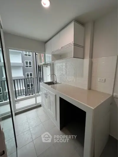 Modern kitchen with sleek cabinetry and balcony access in a contemporary apartment.