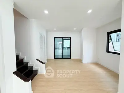 Spacious modern living room with wooden flooring and large windows for natural light.