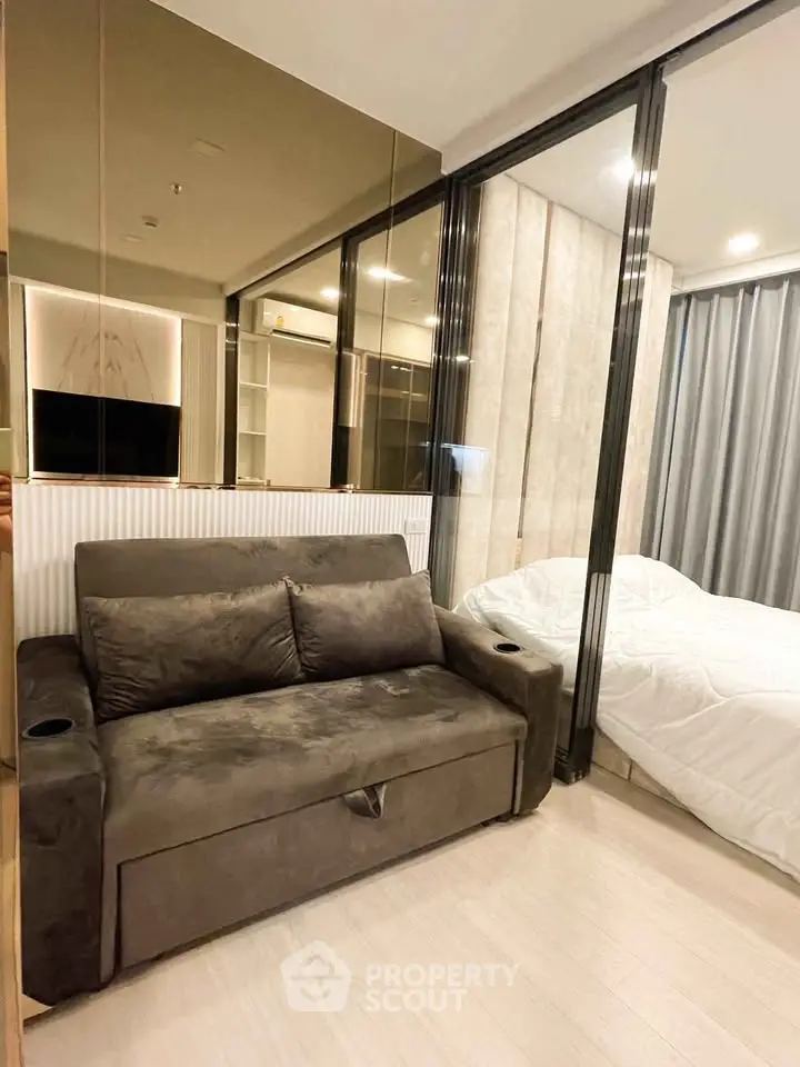 Modern studio apartment with cozy living area and bedroom separated by glass partition.