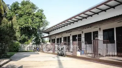 Charming single-story building with gated entrances and lush greenery.