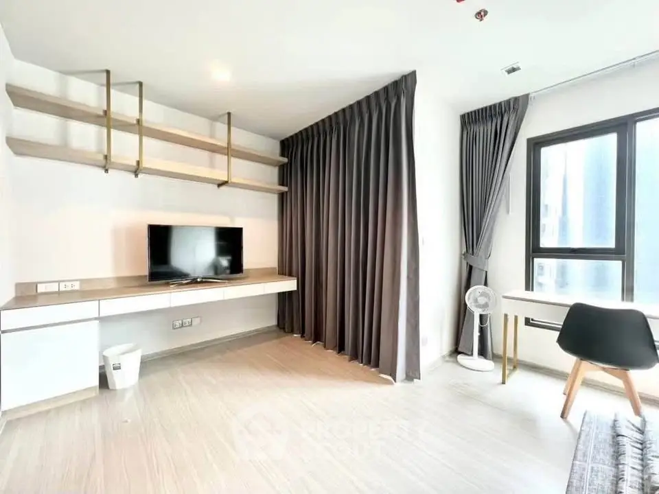 Modern living room with TV, desk, and large window in a bright apartment.