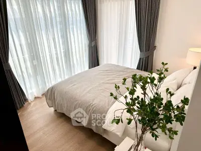 Cozy bedroom with large windows and elegant curtains, featuring a comfortable bed and stylish decor.