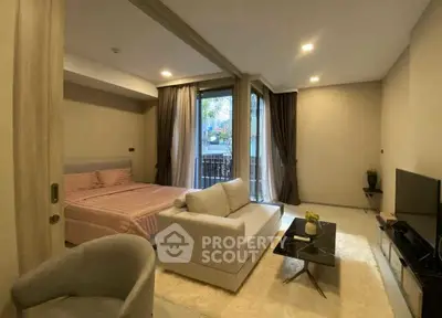 Modern studio apartment with cozy living area and bedroom, featuring a small balcony.