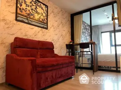 Elegant living space with plush red sofa, marble-textured walls, and sleek flooring leading to a sunlit bedroom with balcony access.