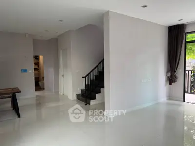 Spacious modern living room with sleek staircase and large windows for natural light.