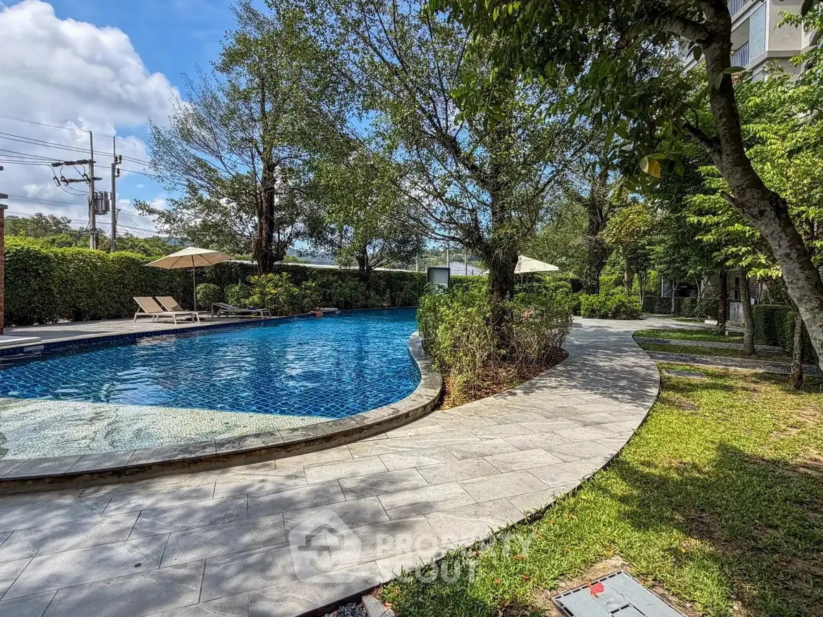 Luxurious outdoor pool area with lush greenery and sun loungers, perfect for relaxation and leisure.