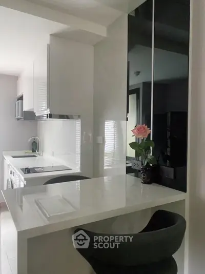 Modern kitchen with sleek white countertops and black accents, featuring a stylish breakfast bar and elegant decor.