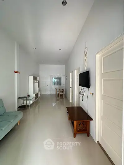 Spacious living room with modern decor and natural light, featuring a wall-mounted TV and elegant furniture.