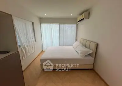 Spacious bedroom with natural light and modern air conditioning unit.