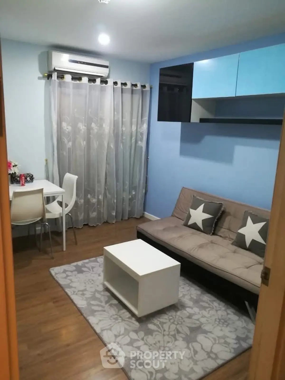 Cozy living room with modern decor, featuring a stylish sofa, dining area, and air conditioning.