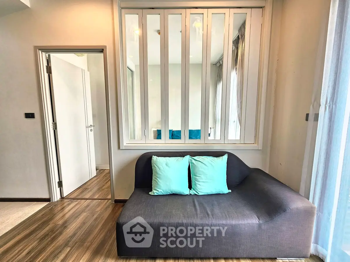 Modern living room with stylish sofa and wooden flooring, featuring a chic partition wall.