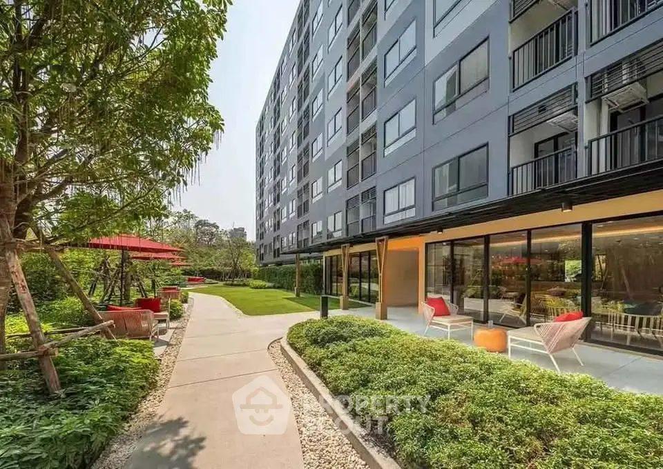 Modern apartment building with lush garden and outdoor seating area, perfect for relaxation.