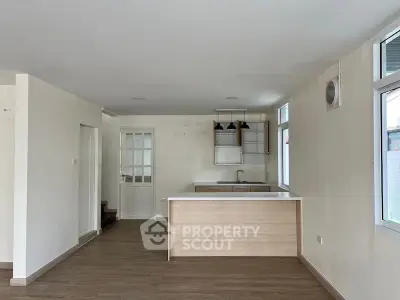 Spacious open-plan living area with modern kitchen, ample natural light, and sleek wooden flooring, ideal for entertaining and comfortable living.