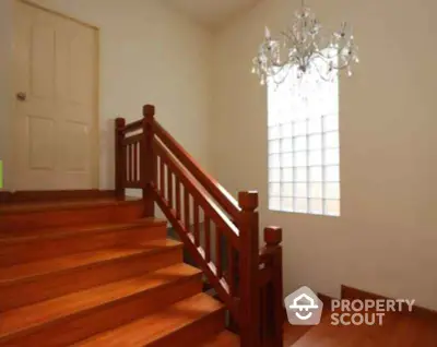 Elegant wooden staircase with chandelier and natural light