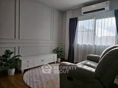 Cozy living room with elegant panel walls and plush seating, featuring natural light from large window.