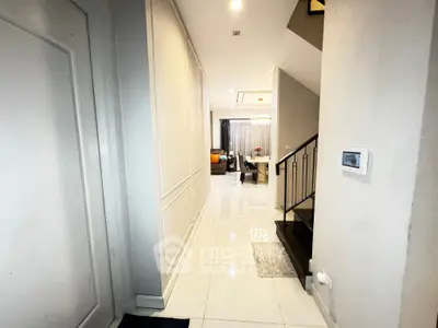 Modern interior hallway leading to a stylish living room with elegant decor.