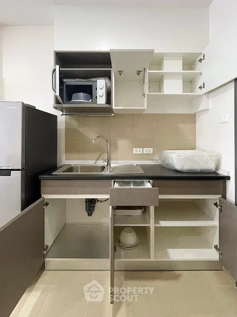 Modern kitchen with sleek cabinetry, stainless steel sink, and microwave in a compact layout.