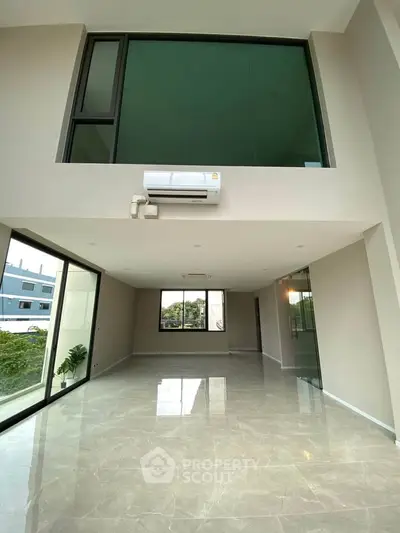 Spacious modern living room with high ceilings and large windows offering natural light.