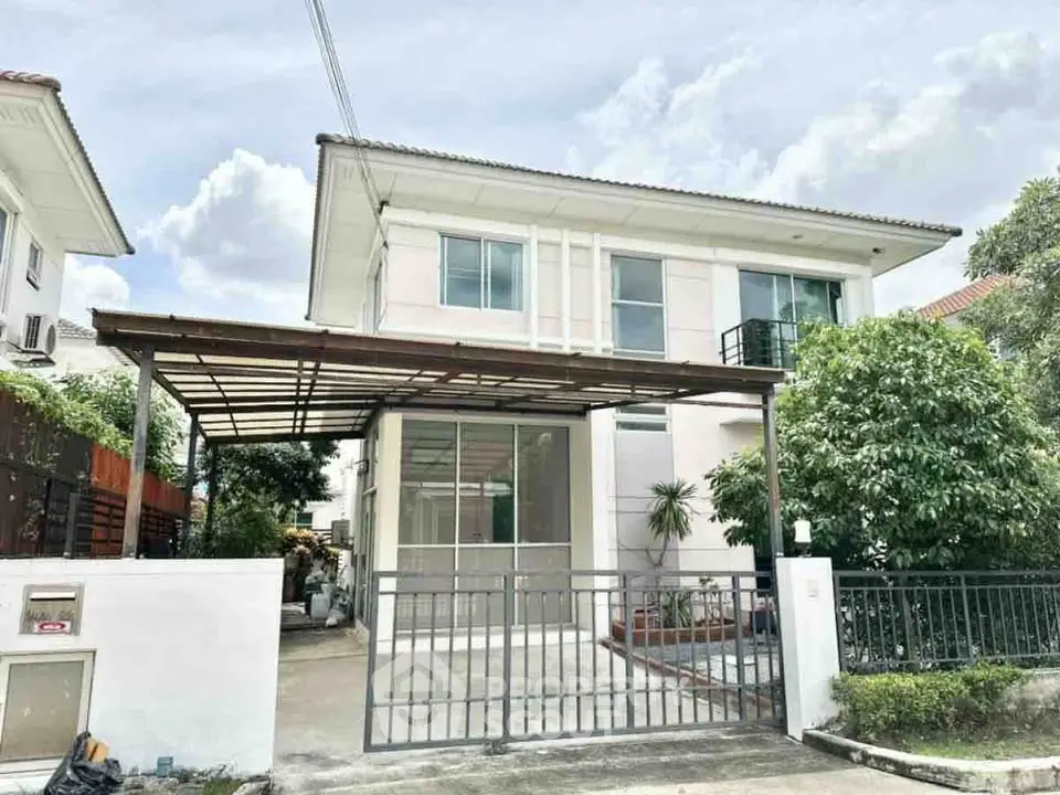 Modern two-story house with gated driveway and lush greenery