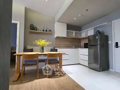 Modern kitchen with dining area, sleek cabinetry, and stainless steel fridge in open layout.