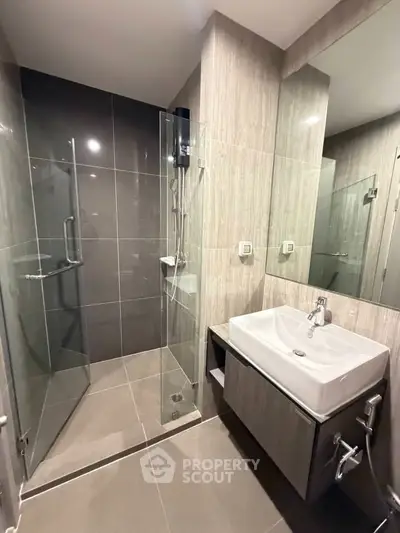 Modern bathroom with sleek glass shower and stylish sink in contemporary apartment.