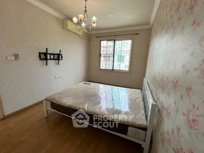 Spacious bedroom with elegant chandelier and large window for natural light.