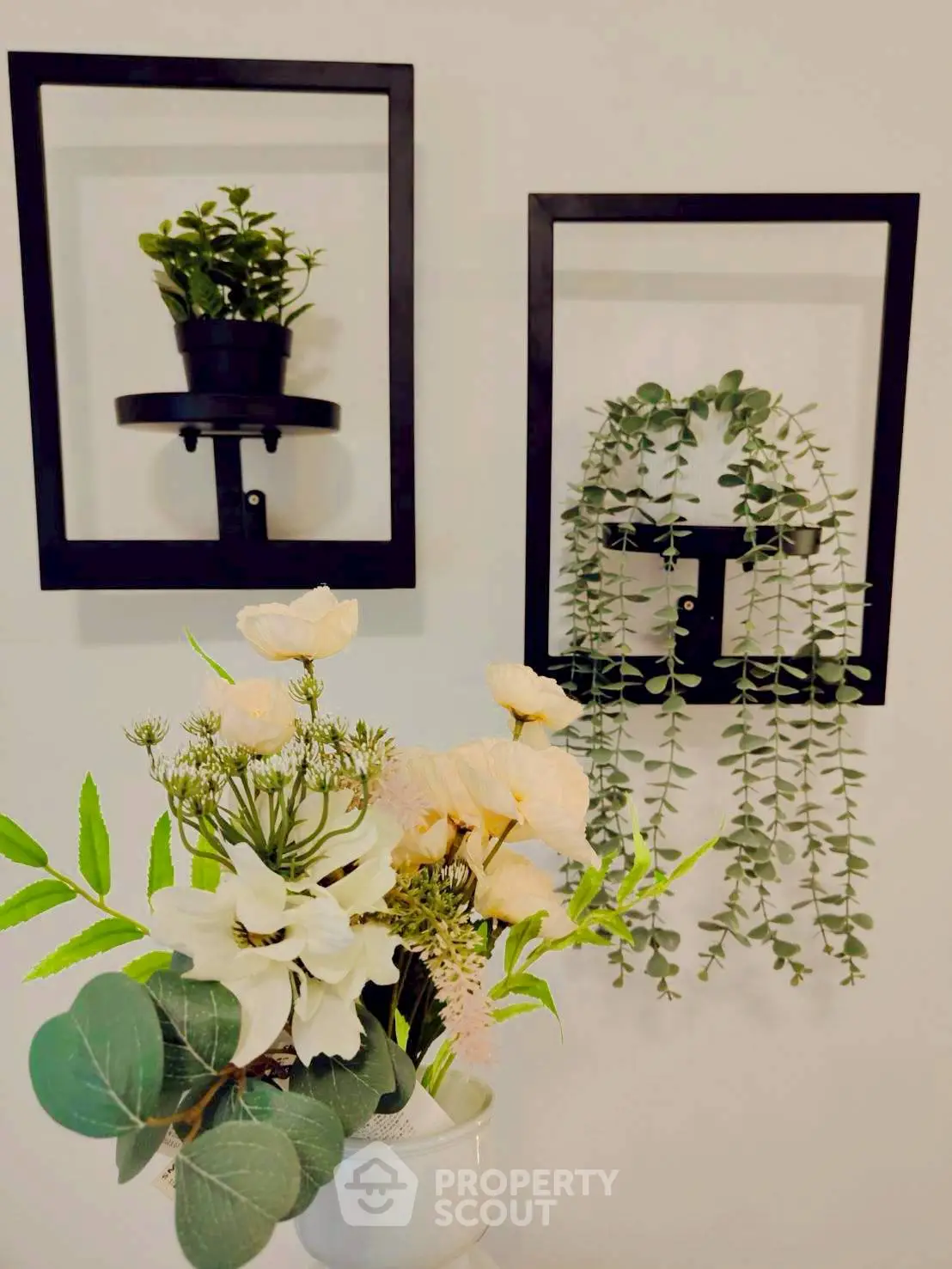 Elegant wall-mounted planters with lush greenery and a vase of fresh flowers for a stylish home decor.