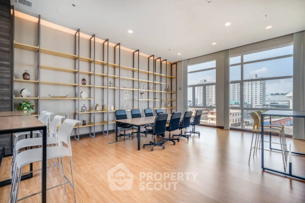 Spacious modern co-working space with large windows and stylish shelving in a high-rise building.