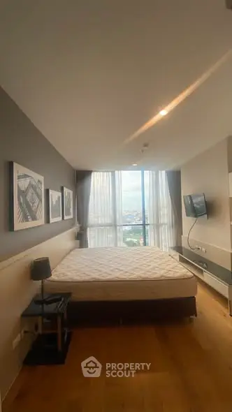Spacious bedroom with large window offering stunning city views and modern decor.