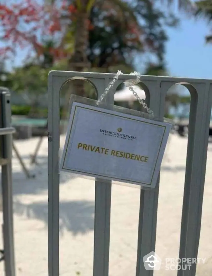 Private residence sign on gate at beachfront property with palm trees.