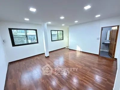 Spacious empty room with wooden flooring and large windows in modern apartment