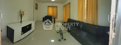 Spacious living room with modern black leather sofa and elegant dining area, perfect for entertaining guests.