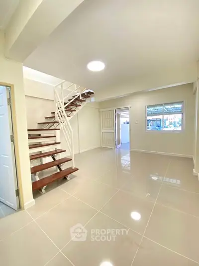 Spacious modern living room with sleek staircase and glossy tiled flooring