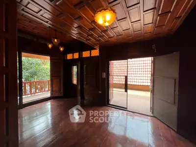 Spacious wooden interior with elegant lighting and large balcony access.