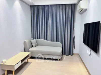 Modern living room with sleek gray sofa and wall-mounted TV, featuring minimalist decor and air conditioning.